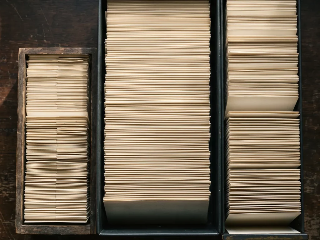 Cenital de tres ficheros de tarjetas de distinto tamaño juntados sobre una mesa oscura, con las fichas a tres alturas que no llegan a casar.